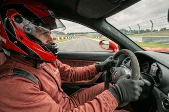 Pilote en combinaison de course concentré au volant d'une voiture de sport sur un circuit de pilotage professionnel